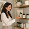 Smiling woman with probiotics, magnesium and wellness gummies on a bright kitchen table