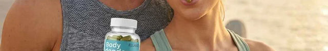 A man and a woman standing together outdoors near the water at sunset, with the man holding a bottle of ellasie body supplement capsules. The man wears a gray sleeveless athletic tank top, and the woman wears a light sage green ribbed tank top.